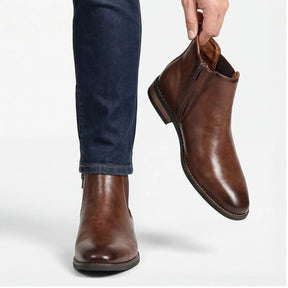 Modelo masculino segurando bota Chelsea marrom