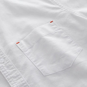 Detalhe do bolso frontal e do bordado discreto da camisa masculina branca