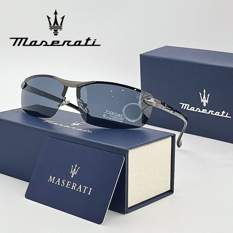 Óculos de sol Maserati com lentes escuras e armação metálica, apoiados sobre estojo azul da marca, com cartão e logotipo Maserati ao fundo.